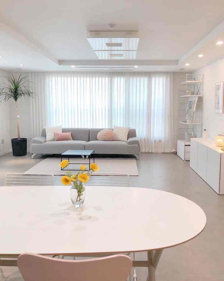 White and gray toned living room featuring a simple sofa and yellow flower decoration with a clean, spacious atmosphere
