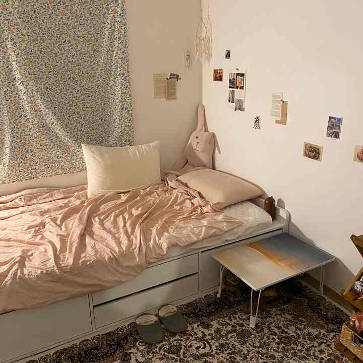 Soft white and orange-toned bedroom featuring a bed, patterned carpet, and a small nightstand creating a cozy atmosphere
