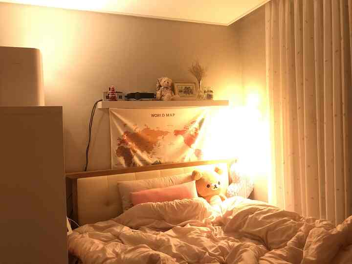 Warm beige-toned bedroom featuring a large bed, wall decor, and charming shelf objects creating a cozy atmosphere