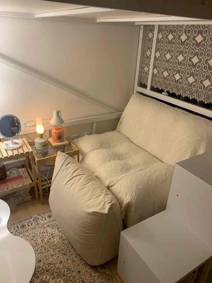 Cozy living room with light gray walls and beige sofa featuring soft cushions and lace decor