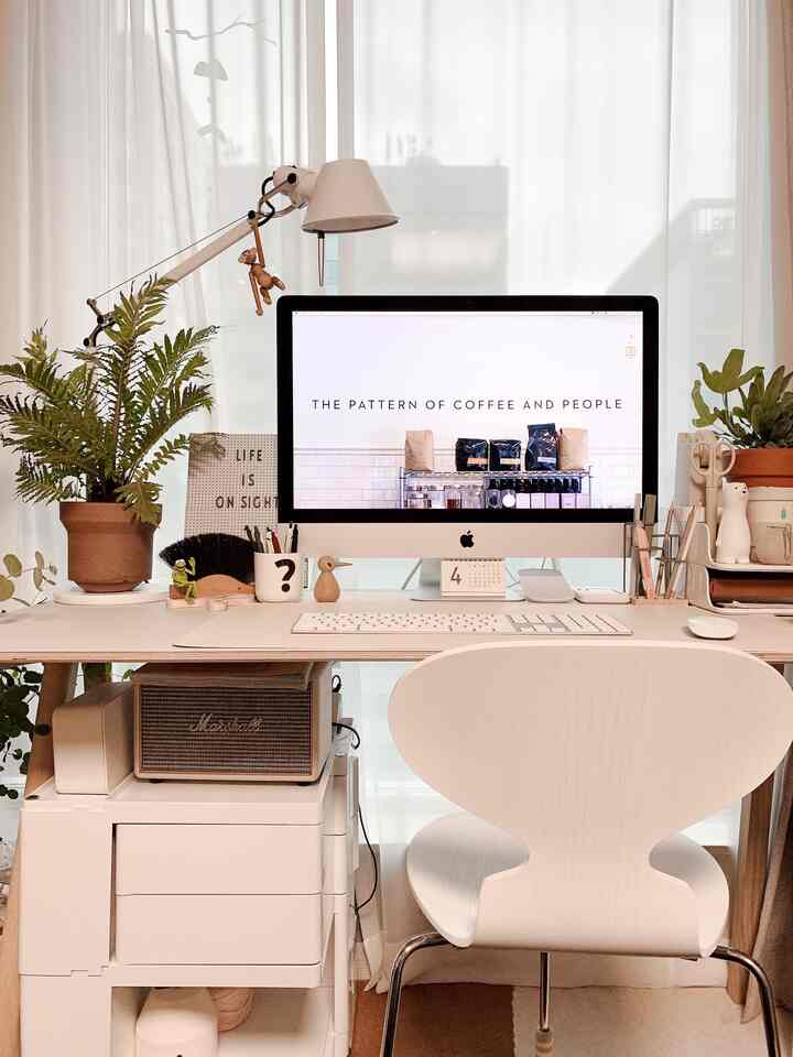 Bright white-toned home office workspace featuring a clean desk with an iMac and plants, creating a cozy atmosphere