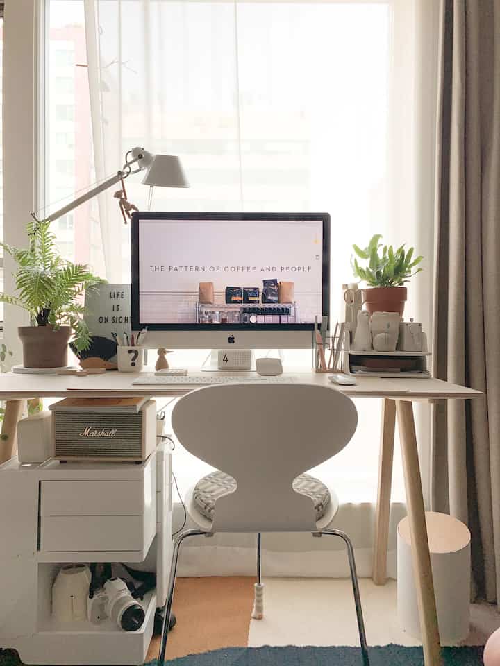 明るいホワイトと木目調のモダンでシンプルなホームオフィス、デスク上のパソコンと植物が調和した雰囲気のあるインテリア