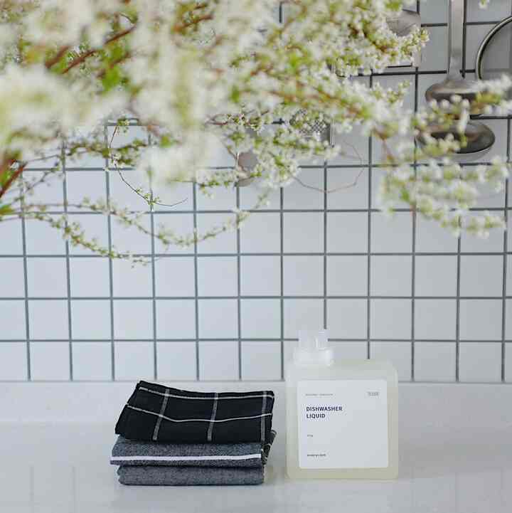 白とグレーのトーンのキッチン、キッチンタオルと食器洗い機用洗剤が配置されたシンプルで清潔感のあるインテリア