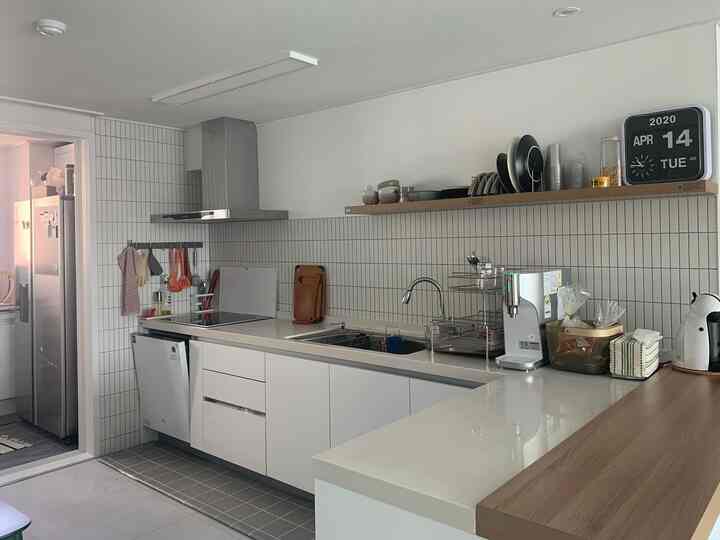 White and wood tone kitchen without upper cabinets, featuring a clean and warm atmosphere