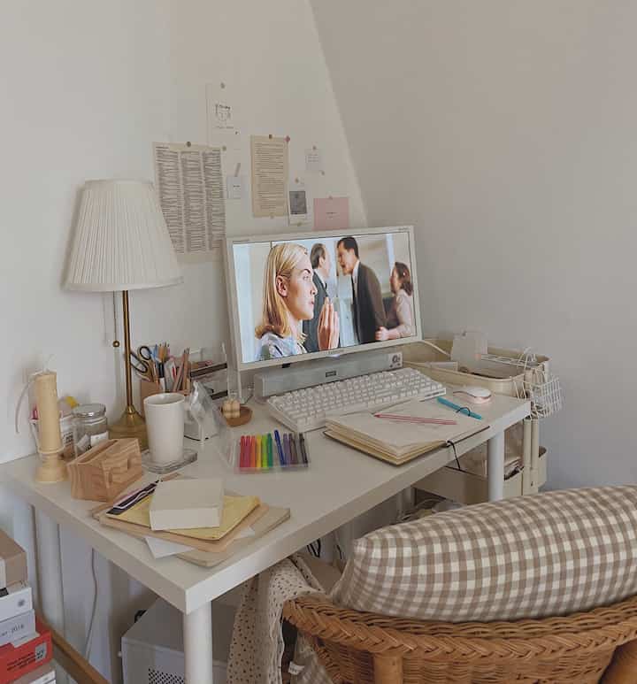 白とベージュのトーンのワンルームホームオフィス、デスクと椅子、テーブルランプが配置されたシンプルでヴィンテージな空間