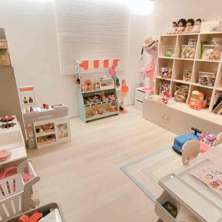 ホワイトとウッドトーンの子供部屋、玩具収納と本棚が配置された落ち着いた印象のインテリア