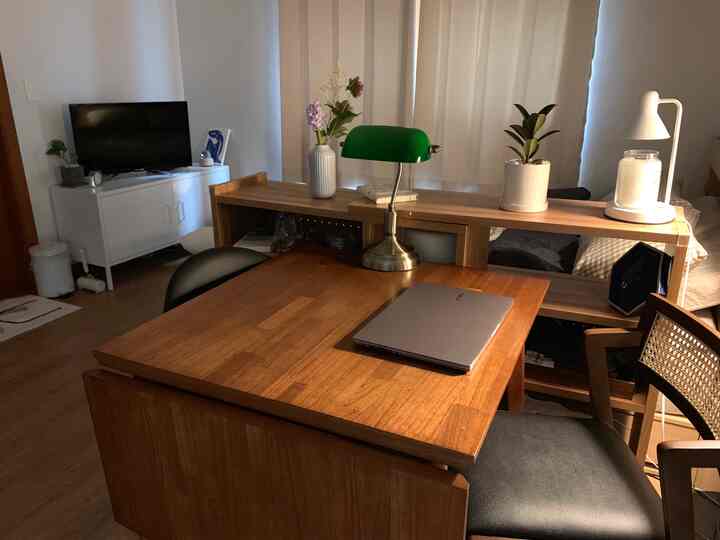 Natural wood tone and white two-person home office and dining space with key furniture and plants