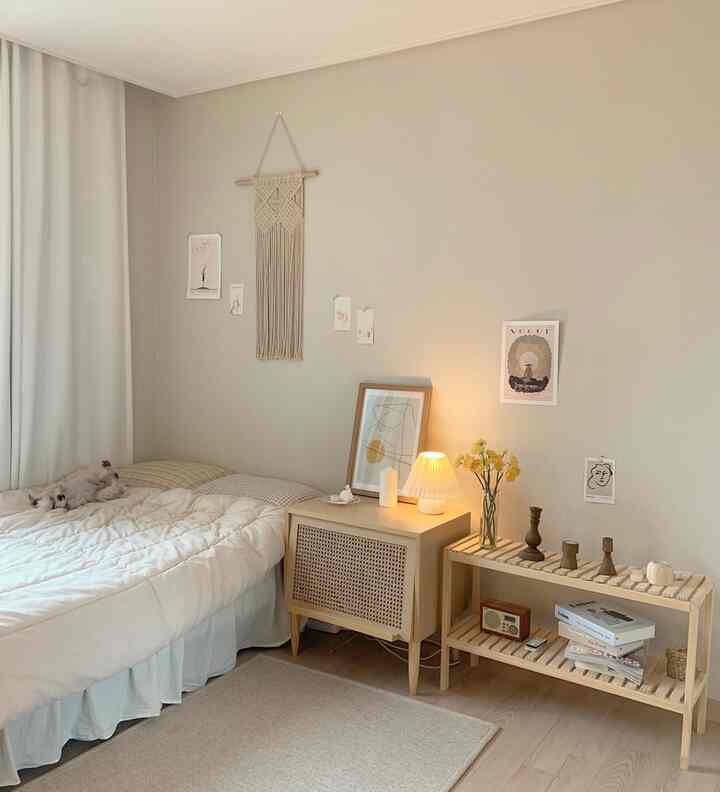 A beige and natural toned bedroom featuring a bed, wooden nightstand, and decorative elements creating a cozy atmosphere