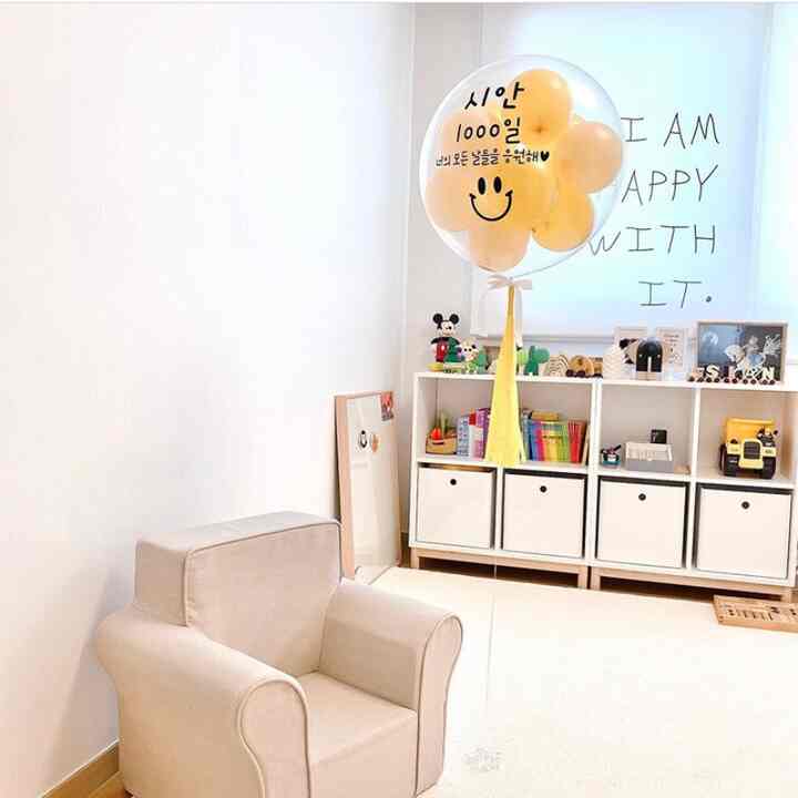 Beige and white toned kids' room featuring beige baby sofa, large rug, and neat storage unit with a simple atmosphere