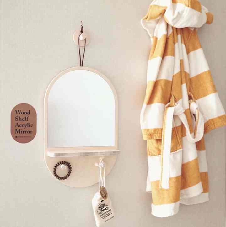 Bright beige wood-tone mirror and yellow-white striped baby bathrobe hanging on bathroom wall