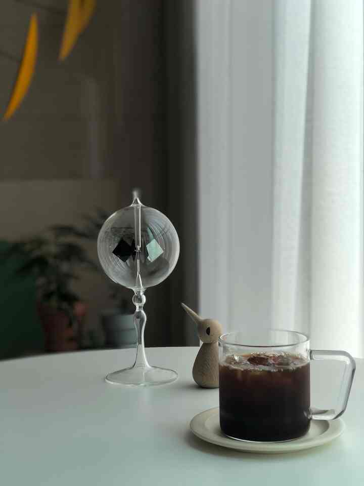 ホワイトトーンのリビングスペース、透明なラジオメーターと木製のオブジェが丸テーブルの上に置かれ、居心地の良いおうちカフェの雰囲気を演出しています