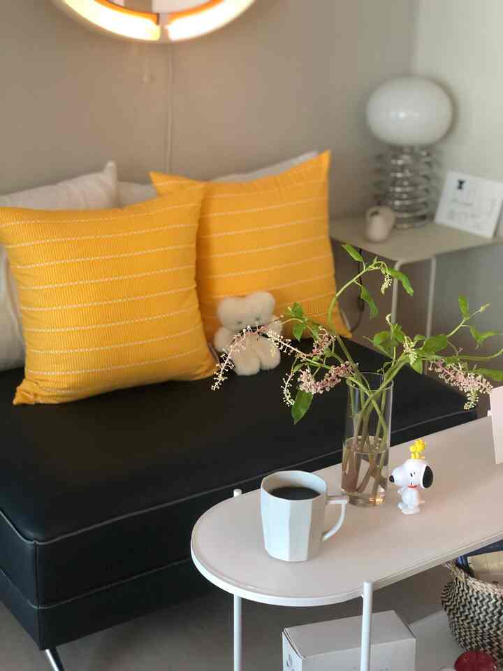 Cozy living room with black sofa featuring yellow cushions and a white coffee table decorated with vase and objects