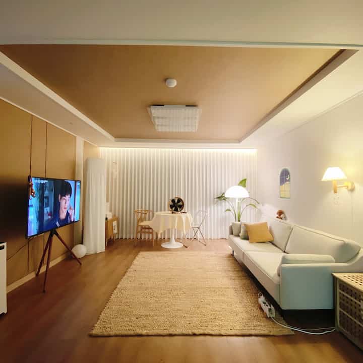 ベージュの天井と床、白いソファとカーテンが配置された明るくシンプルなリビング