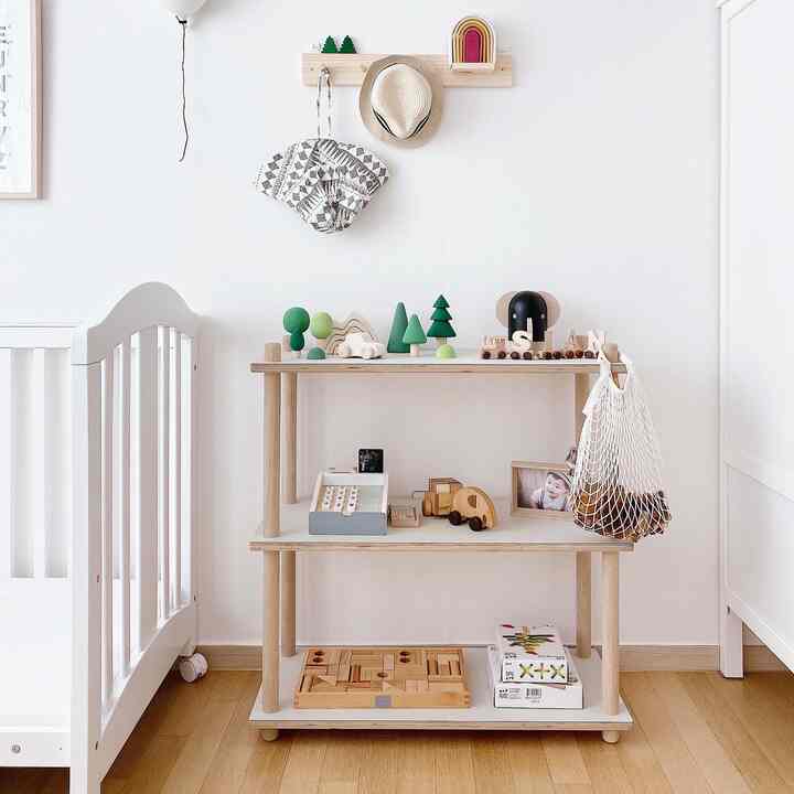 ナチュラルカラーとホワイトの子供部屋、木製の棚に赤ちゃんのおもちゃが整頓された落ち着いたインテリア