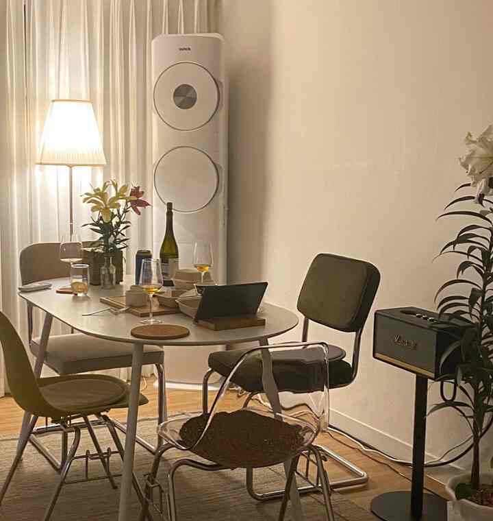 A cozy dining room in white and beige tones featuring an oval dining table with assorted chairs and soft ambient lighting