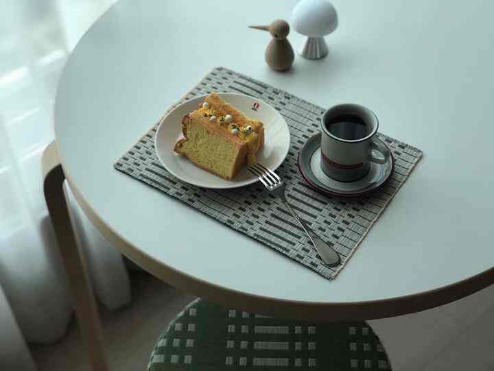 White-toned round dining table featuring cake and coffee cup in a cozy home cafe setting