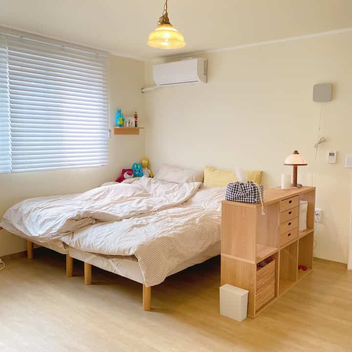 Beige-toned bedroom featuring beige check-pattern bedding and natural wood furniture creating a cozy atmosphere