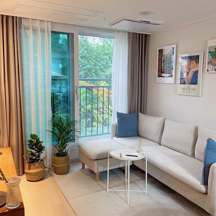 Cozy living room in beige and wood tones featuring fabric sofa with blue cushions, framed art, and indoor plants in harmony