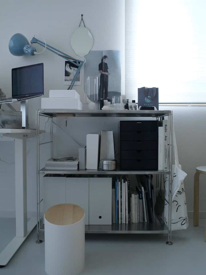 白とメタルトーンのホームオフィス、金属製の棚とデスクランプが配置された整頓された作業空間