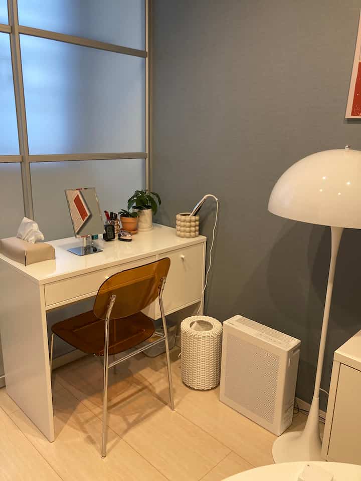 A compact room with sky blue walls featuring a white vanity desk and chair in white and beige tones, creating a neat atmosphere