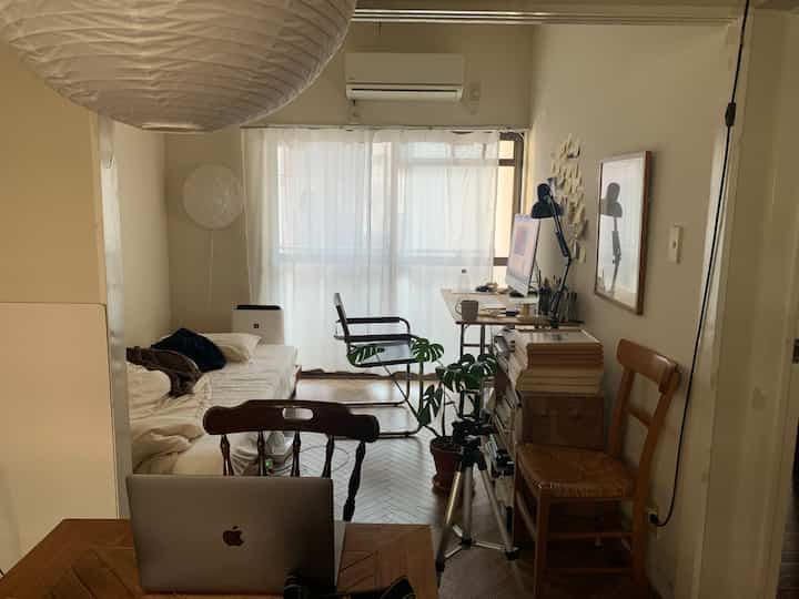 ナチュラルな色調の小さな6畳のホームオフィス、白いカーテンとソファ、木製家具が配置された居心地の良い作業空間