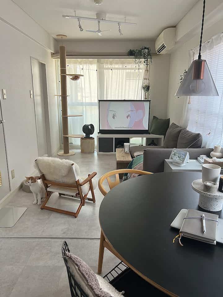 Ivory-toned living room featuring a round table, sofa, and cat tower with a natural atmosphere