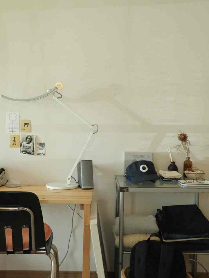 白い壁と木製デスクがある落ち着いたホームオフィス空間、テーブルランプと金属製の収納棚が配置された印象的なインテリア