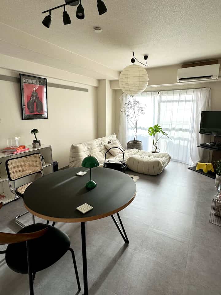 白とグレーの色調の二人暮らしリビング、ミッドセンチュリーモダンのソファとダイニングテーブルが配置された自然な雰囲気のあるインテリア