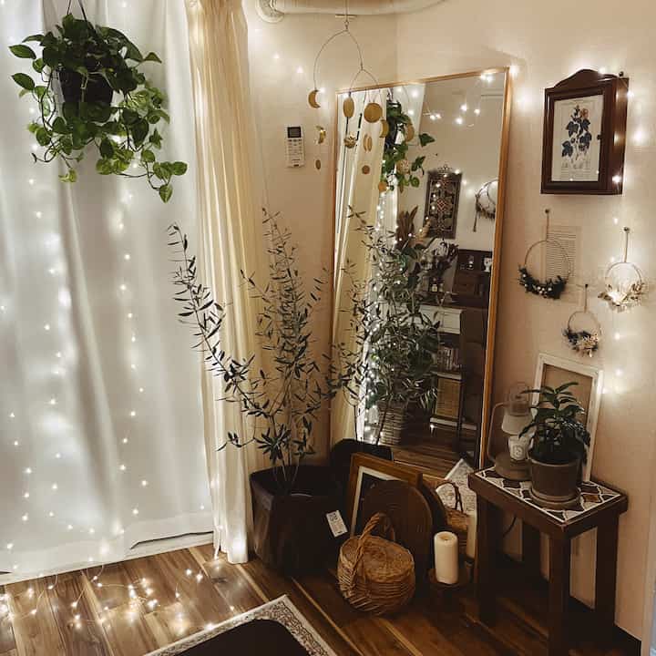 Cozy powder room with warm wood tones and gold accents, featuring plants and a brass mobile with soft string lights