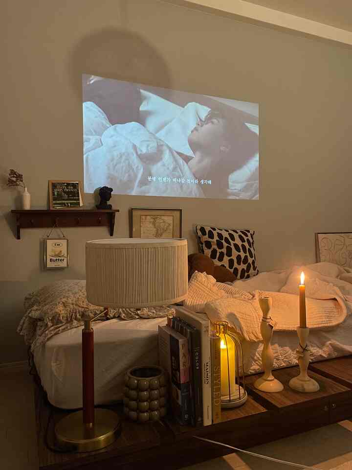 Natural tone bedroom featuring wooden bed frame, warm lighting, and projector screen creating a cozy atmosphere