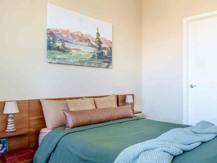 A minimalist and simple bedroom featuring a natural tone bed with beige walls