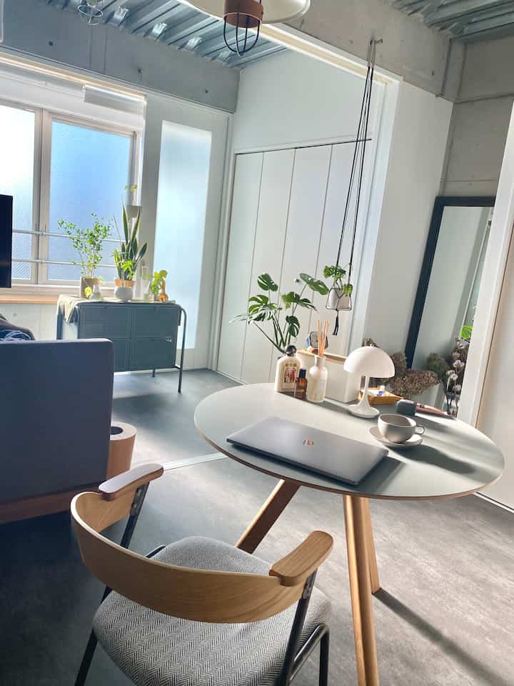 明るいホワイトと木目調が調和したリビング、丸テーブルと椅子、植物が配置されたミニマルな雰囲気のホームカフェ空間