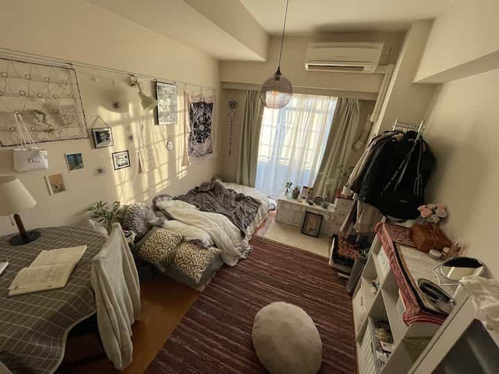 Beige and brown toned studio bedroom featuring bed and table in a cozy space