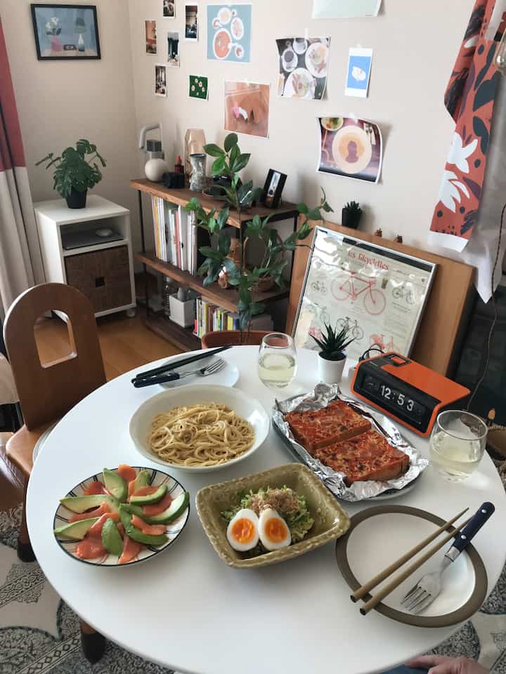 White and wood tone dining room featuring a cozy table with food and wall posters, creating a warm atmosphere