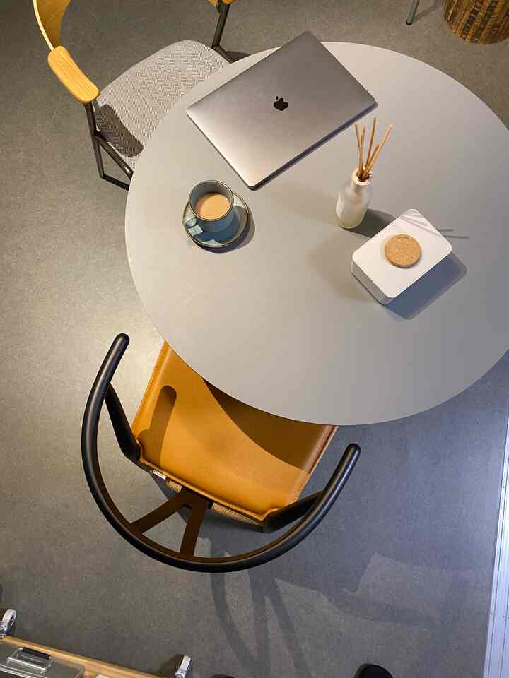 Gray round dining table with Nordic-style dining chairs in a minimalist home office setting