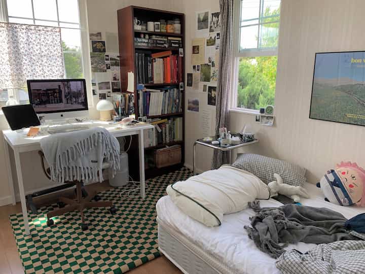 Natural-toned small bedroom featuring desk and bookshelf with simple and open atmosphere