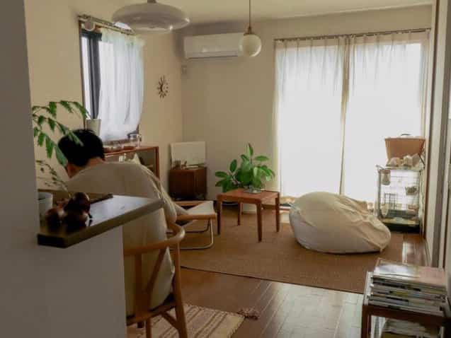 暖かいナチュラル色調のリビング、コーヒーテーブルとビーズクッション、植物が調和した雰囲気のあるインテリア