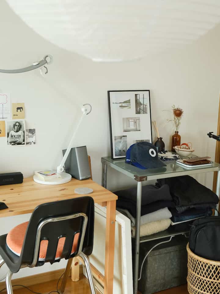 Natural wood tone floor and desk in a single household home office for remote work, with a somewhat cluttered indoor atmosphere