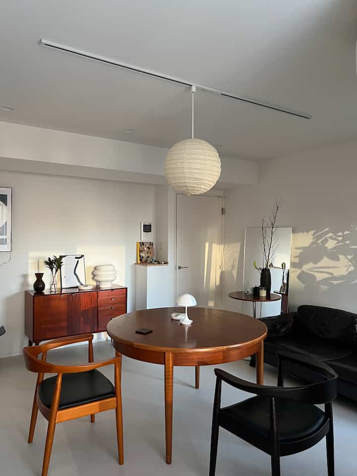 A natural modern living and dining room with white walls, ceiling, and brown round dining table with chairs