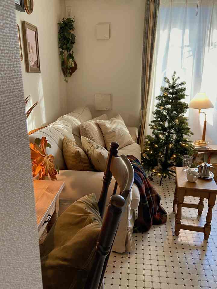 白とベージュの落ち着いたリビング、ファブリックソファとクリスマスツリー、テーブルランプが温かみのある空間を演出