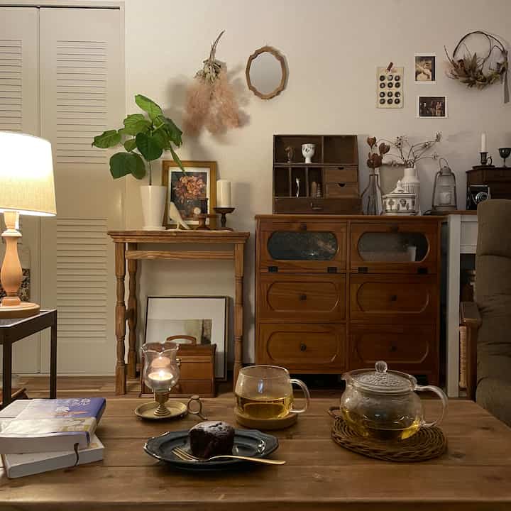 ブラウンの木目調と白い壁が調和する居心地の良いリビング、ティーセットとレトロな家具が配置された雰囲気のあるインテリア