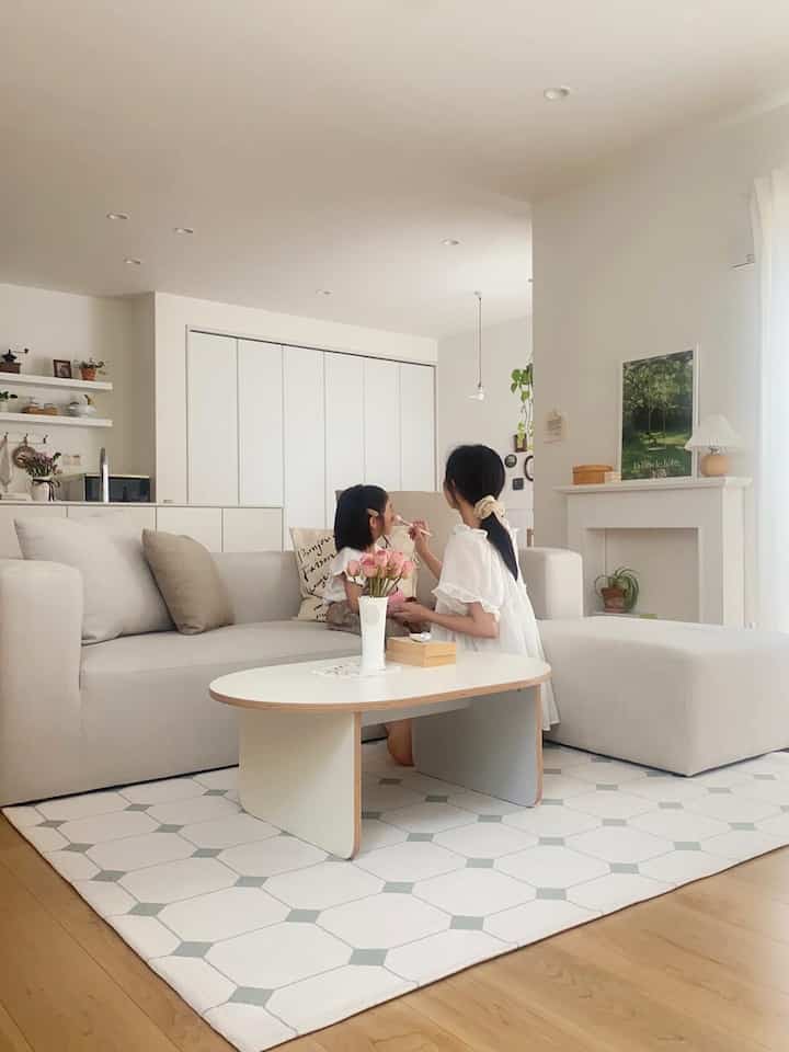 Soft beige and white toned living room featuring a spacious sofa and ottoman in a cozy Korean interior