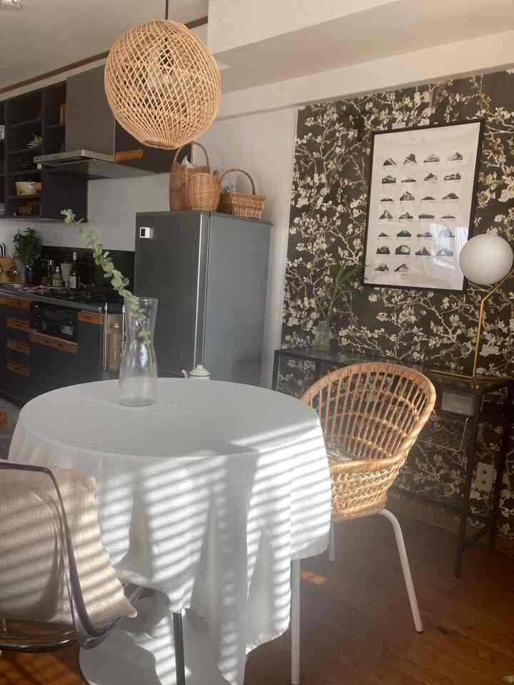 ブラウンとホワイトのナチュラルトーンが調和したダイニング、ラタンチェアと白いテーブルクロスが温かみのある雰囲気を演出するインテリア