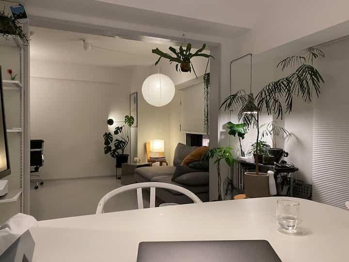 白とグレーを基調としたリビング、グレーのソファと多様な植物が配置されたナチュラルでミニマルな雰囲気のインテリア