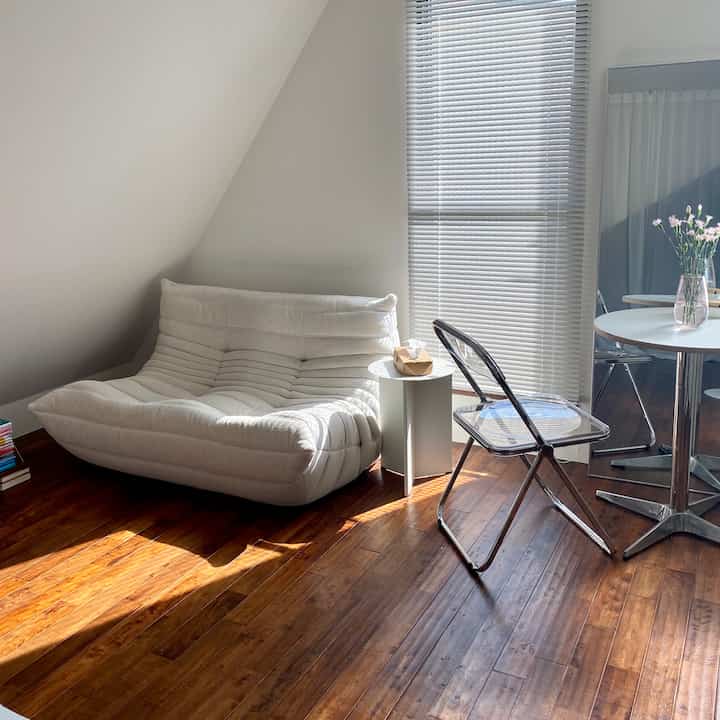 White and wood tone dining room featuring a sofa and transparent chairs in a simple, natural space