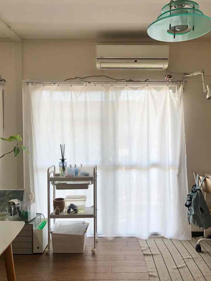 ホワイトとウッドトーンのナチュラルスタイルのホームオフィス空間、デスクとオフィスチェア、収納カートが配置された落ち着いたリビング