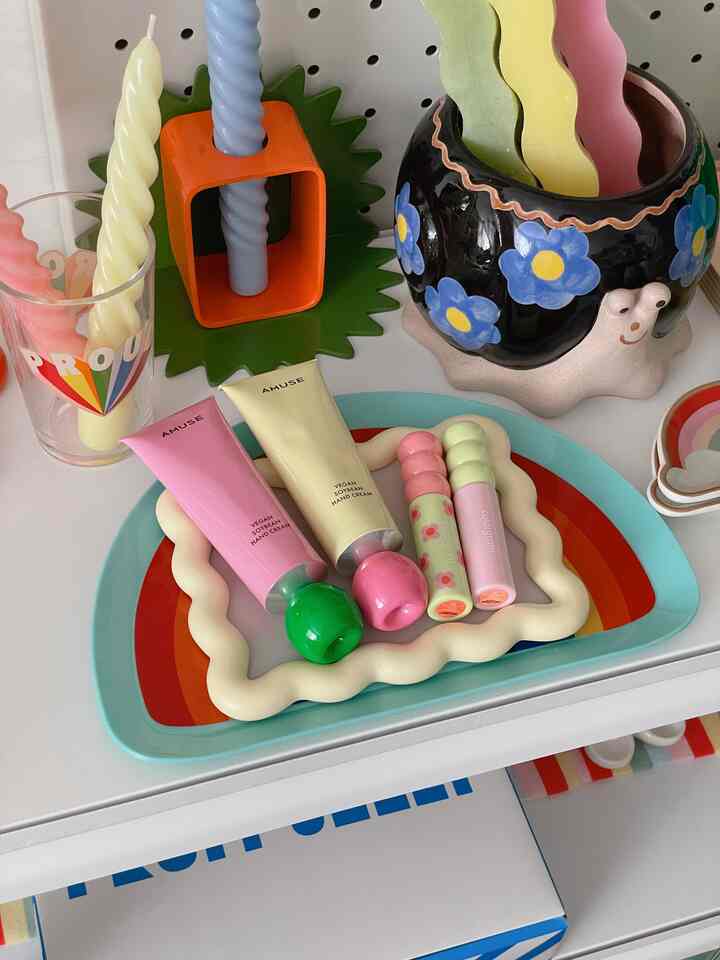 カラフルでレトロな雰囲気の棚の空間、化粧品と装飾小物が遊び心のある形で配置されている