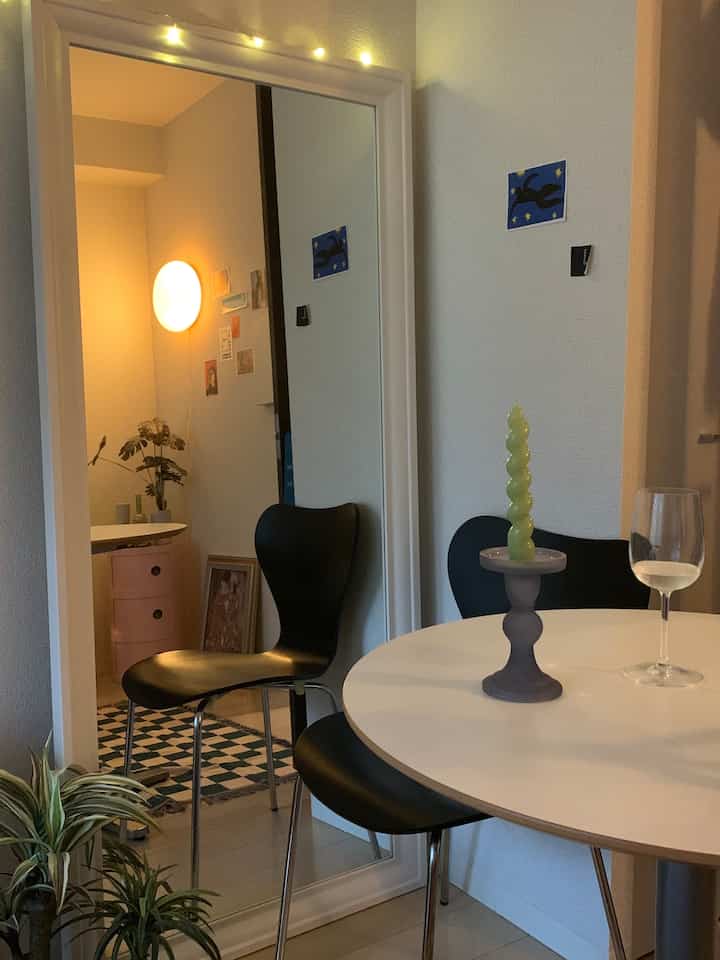 White-toned walls and large mirror featuring black dining chairs and a round dining table in a simple modern dining room