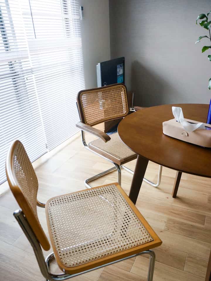 ブラウンと木目調のダイニング、ラタンのチェスカチェアと丸テーブルが配置されたシンプルな空間