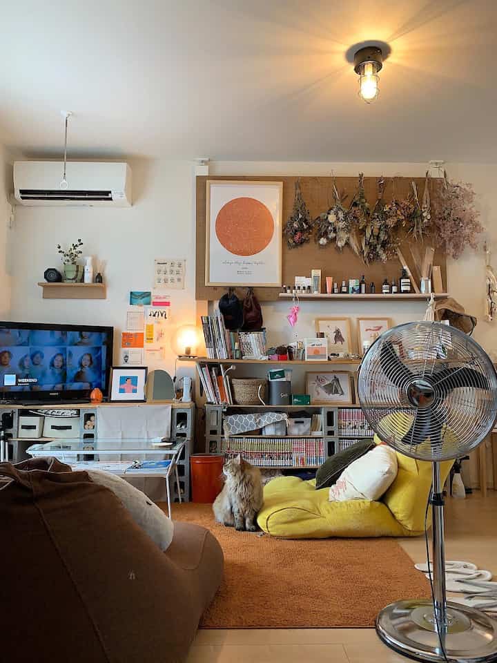 ナチュラルな色調のリビング、黄色の床ソファと茶色のビーズクッション、オレンジのラグ、猫がいる温かみのあるくつろげる空間